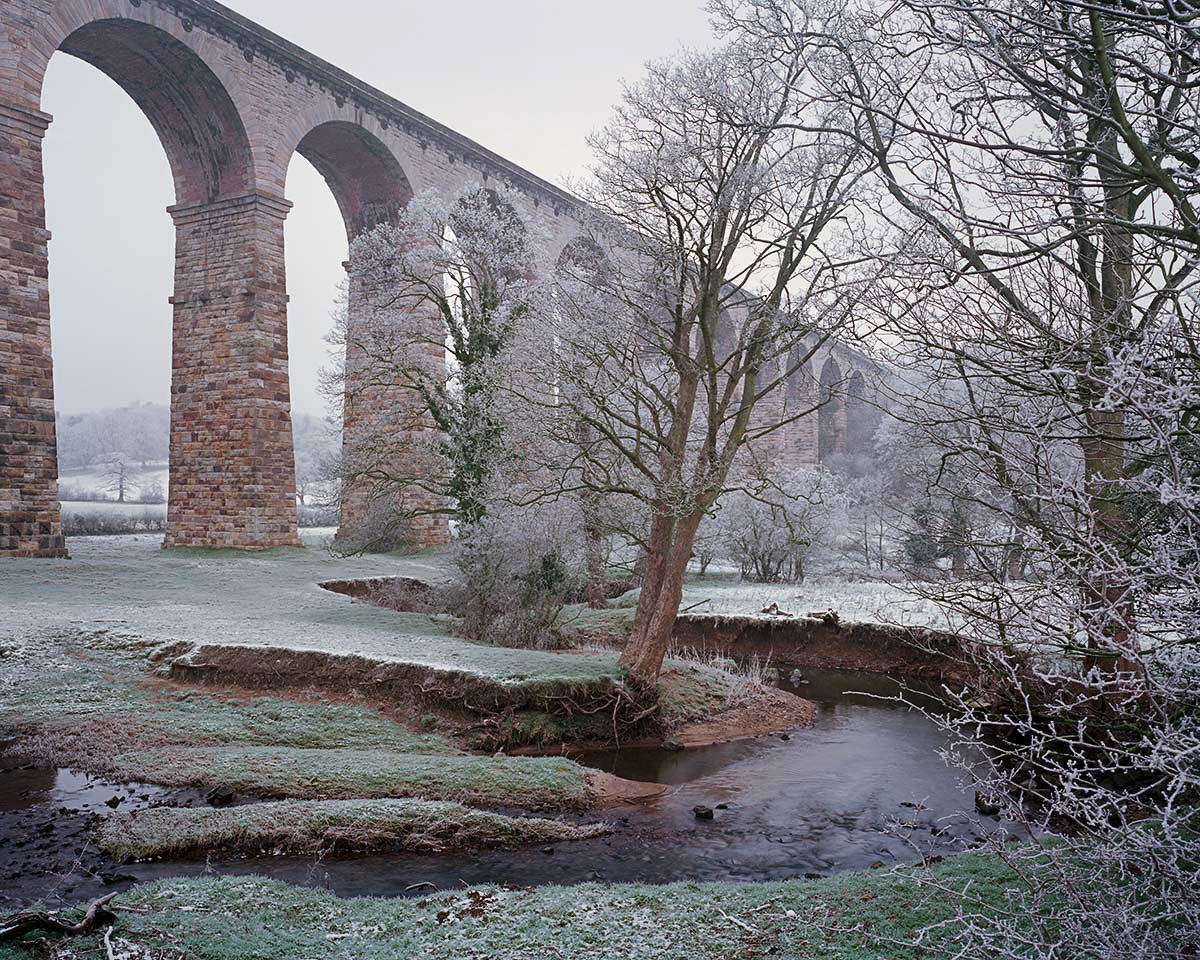 Crimple Valley Viaduct on a frosty winter morning   a house covered in snow