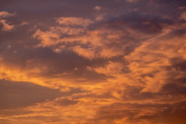 Glowing orange and pink clouds filling a dramatic sky at sunset, with deep purple tones above.