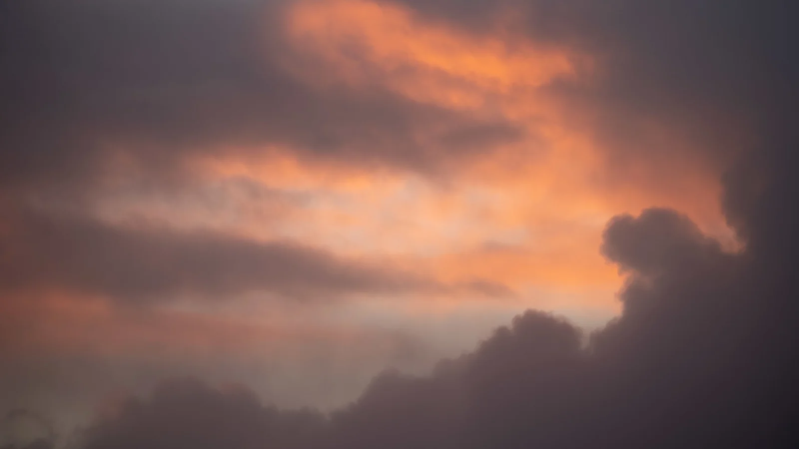 Glowing orange and grey storm clouds at sunset filling a dramatic evening sky