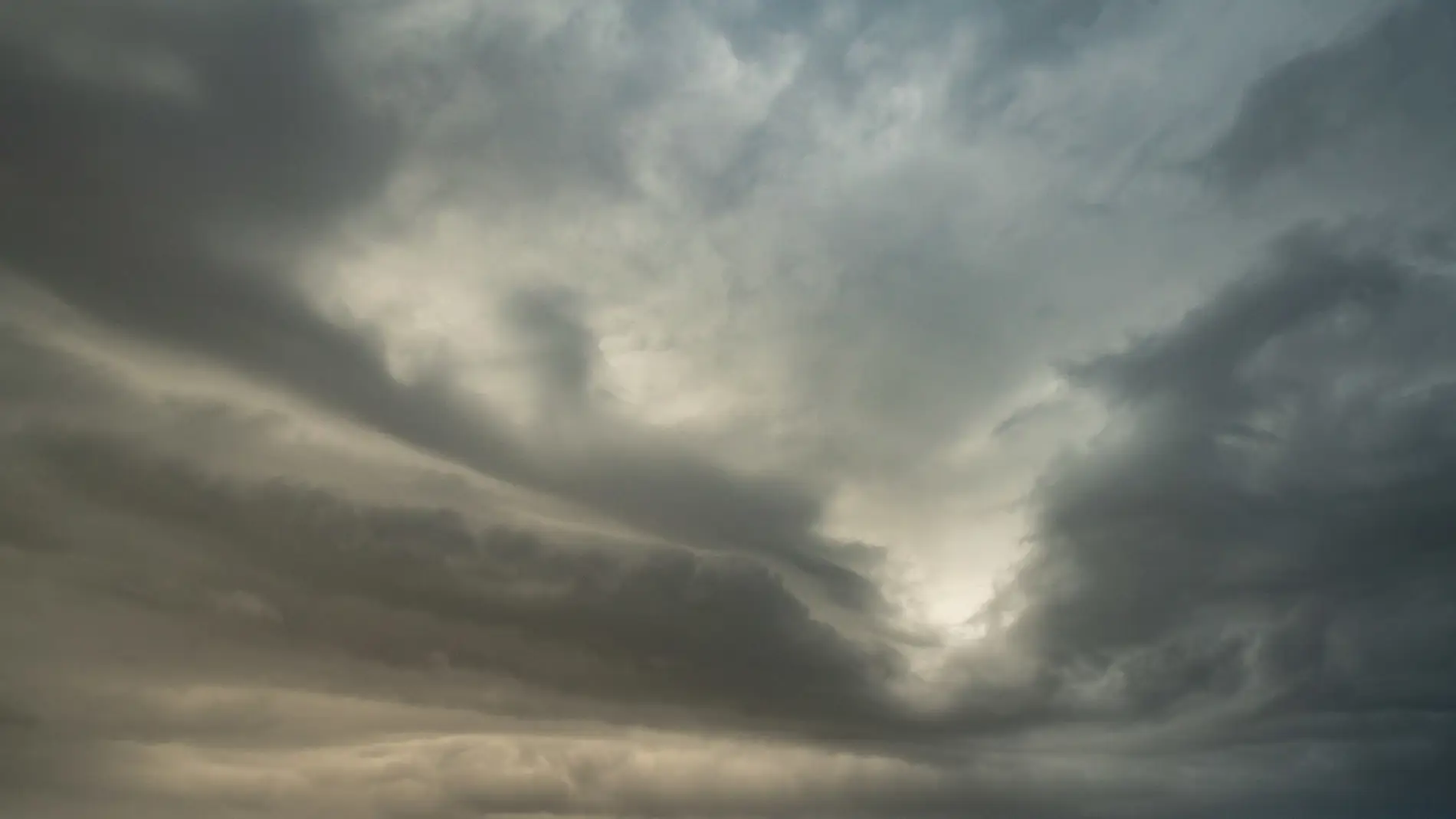 Brooding storm clouds with a faint break of light through a moody overcast sky
