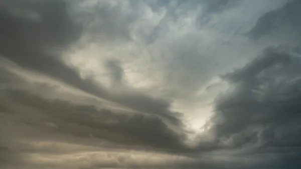 Brooding storm clouds with a faint break of light through a moody overcast sky
