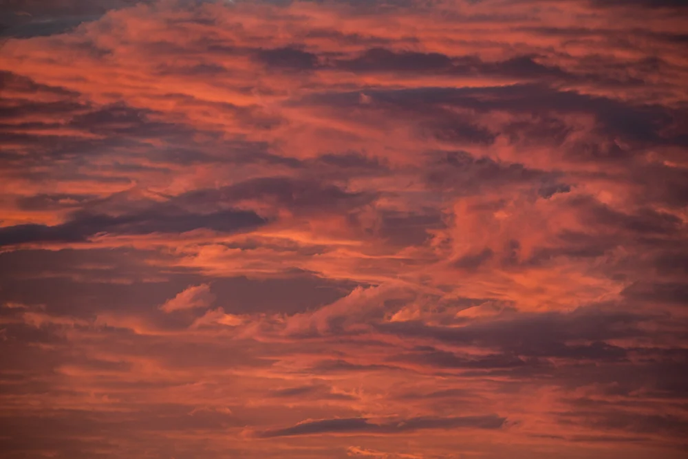 Fiery red and pink clouds glowing across a dramatic sky at sunset