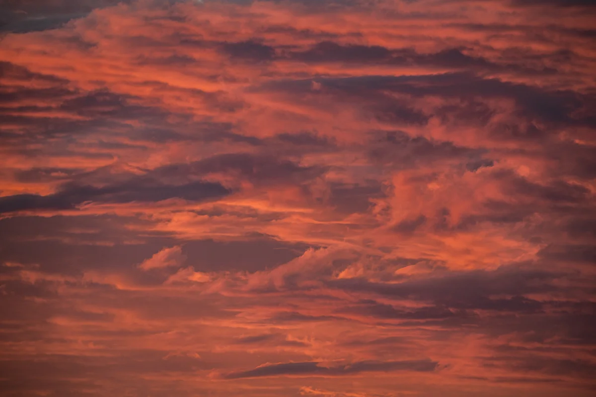 Fiery red and pink clouds glowing across a dramatic sky at sunset