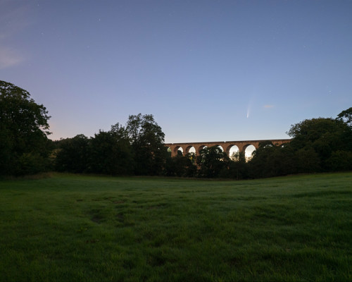 Nightscapes:  a large green field with trees and a building in the background