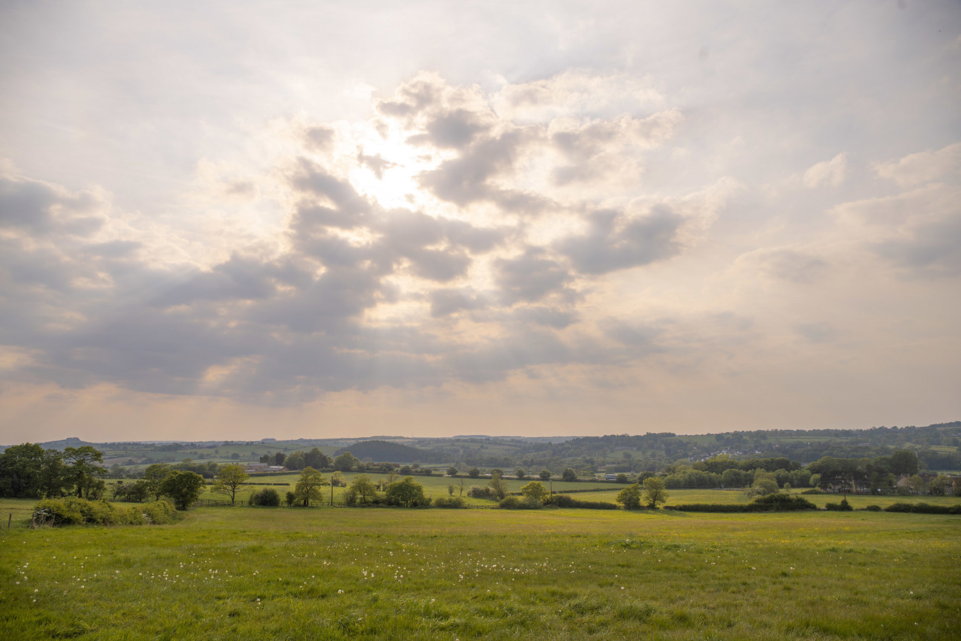  a large green field with clouds in the sky