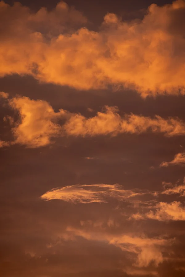 Glowing orange clouds filling a dramatic sky at sunset, lit by warm golden light.