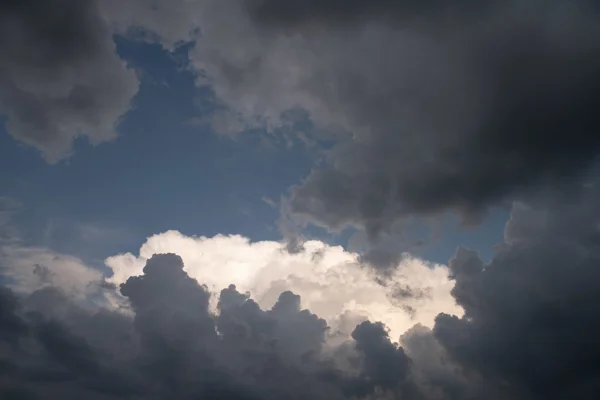 Towering storm clouds with sunlit white tops against patches of blue sky on a stormy afternoon