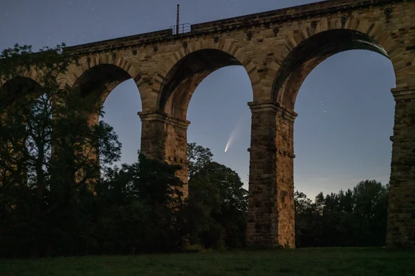 Comet Neowise framed by the arches of Crimple Viaduct against a starry twilight sky