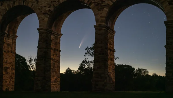 Comet Neowise glowing in the twilight sky framed by the stone arches of Crimple Viaduct.