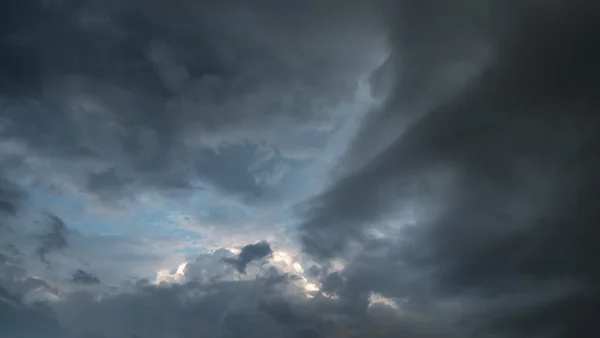 Brooding storm clouds breaking to reveal a glimpse of blue sky and soft light at dusk