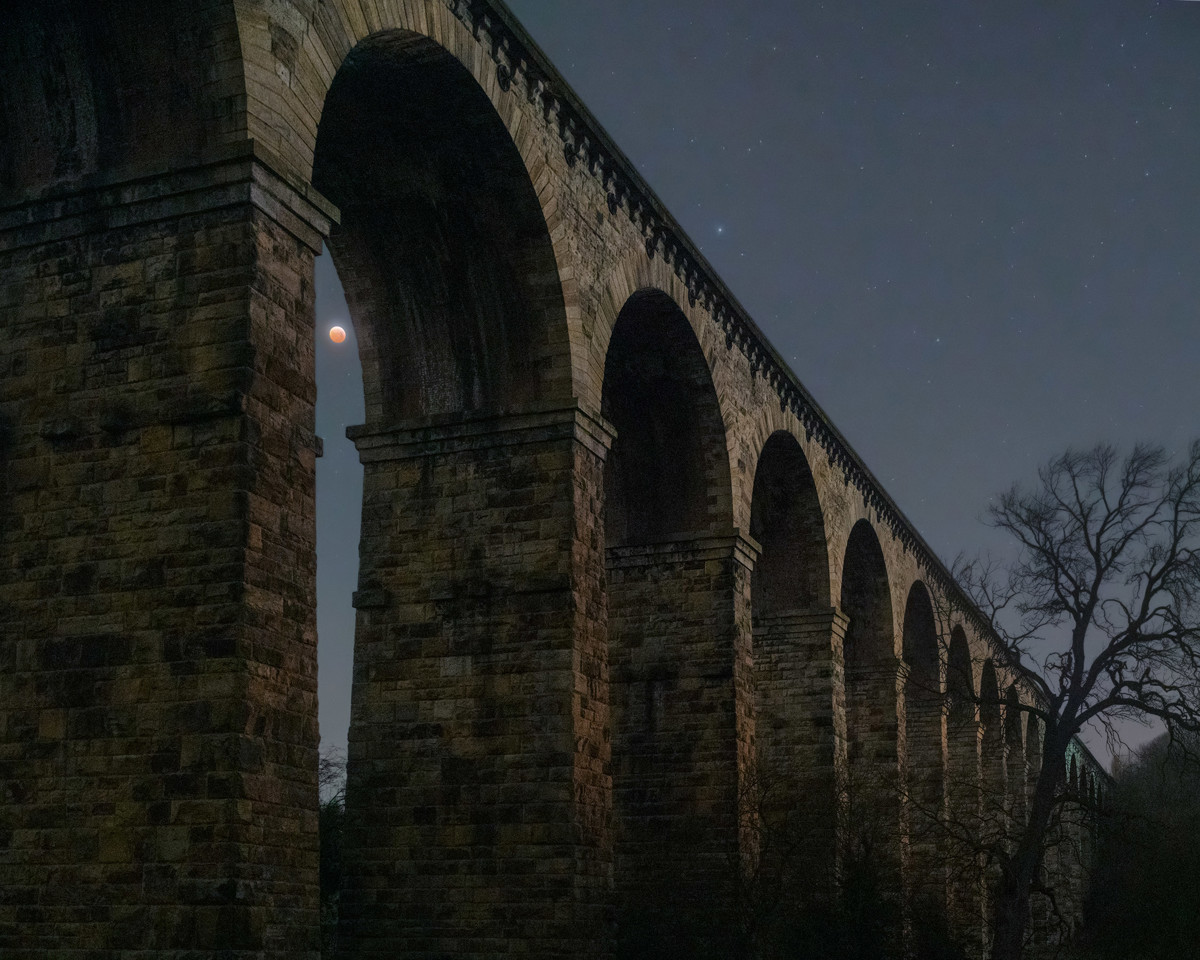  a large stone building with a bridge in the background