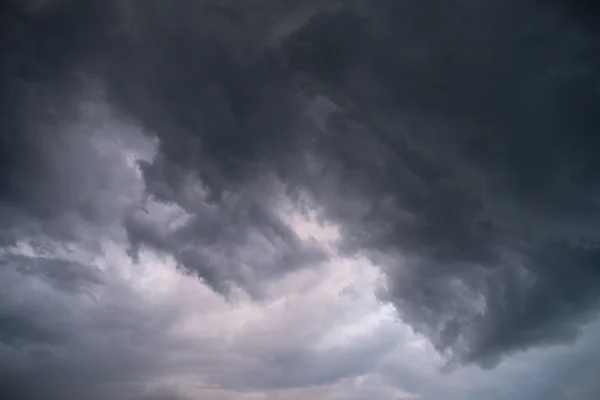 Dark storm clouds gathering across a moody overcast sky in dramatic grey tones