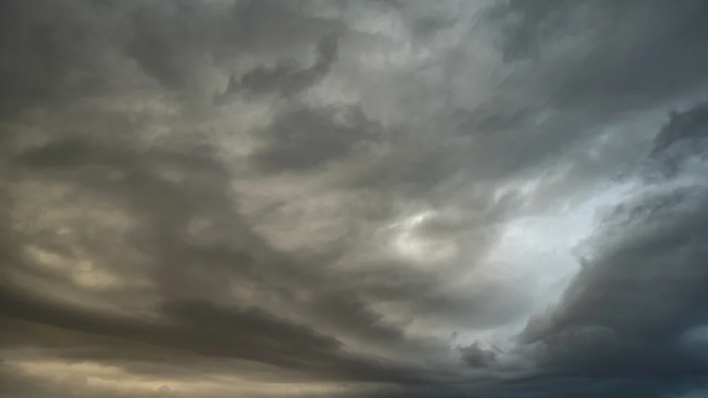 Brooding storm clouds filling a moody grey sky with a faint break of pale light