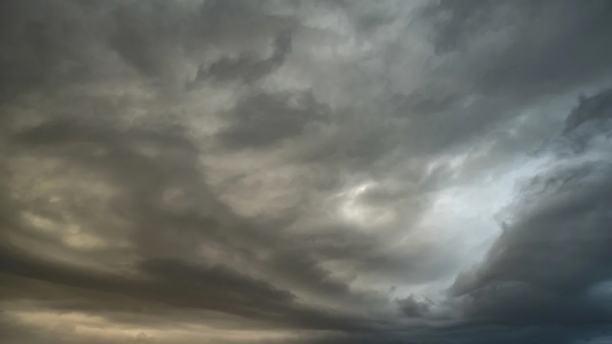 Brooding storm clouds filling a moody grey sky with a faint break of pale light