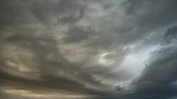 Brooding storm clouds filling a moody grey sky with a faint break of pale light