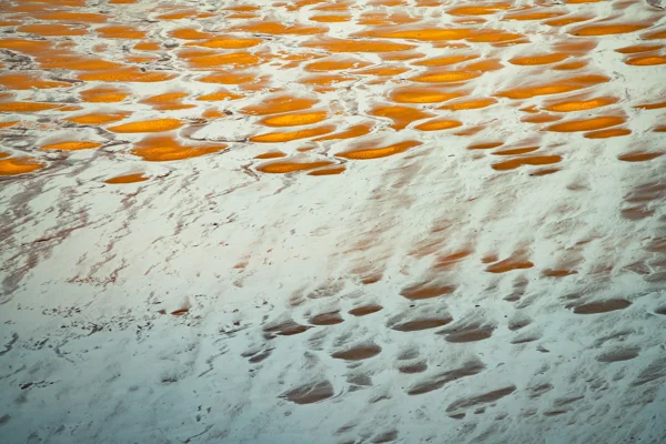 Vibrant orange and white mineral hot springs with steaming pools and mineral deposits on terraced ground.